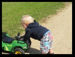 Colin pushes the toy tractor in the gravel