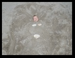 Jared buried in the sand with a sea shell bikini
